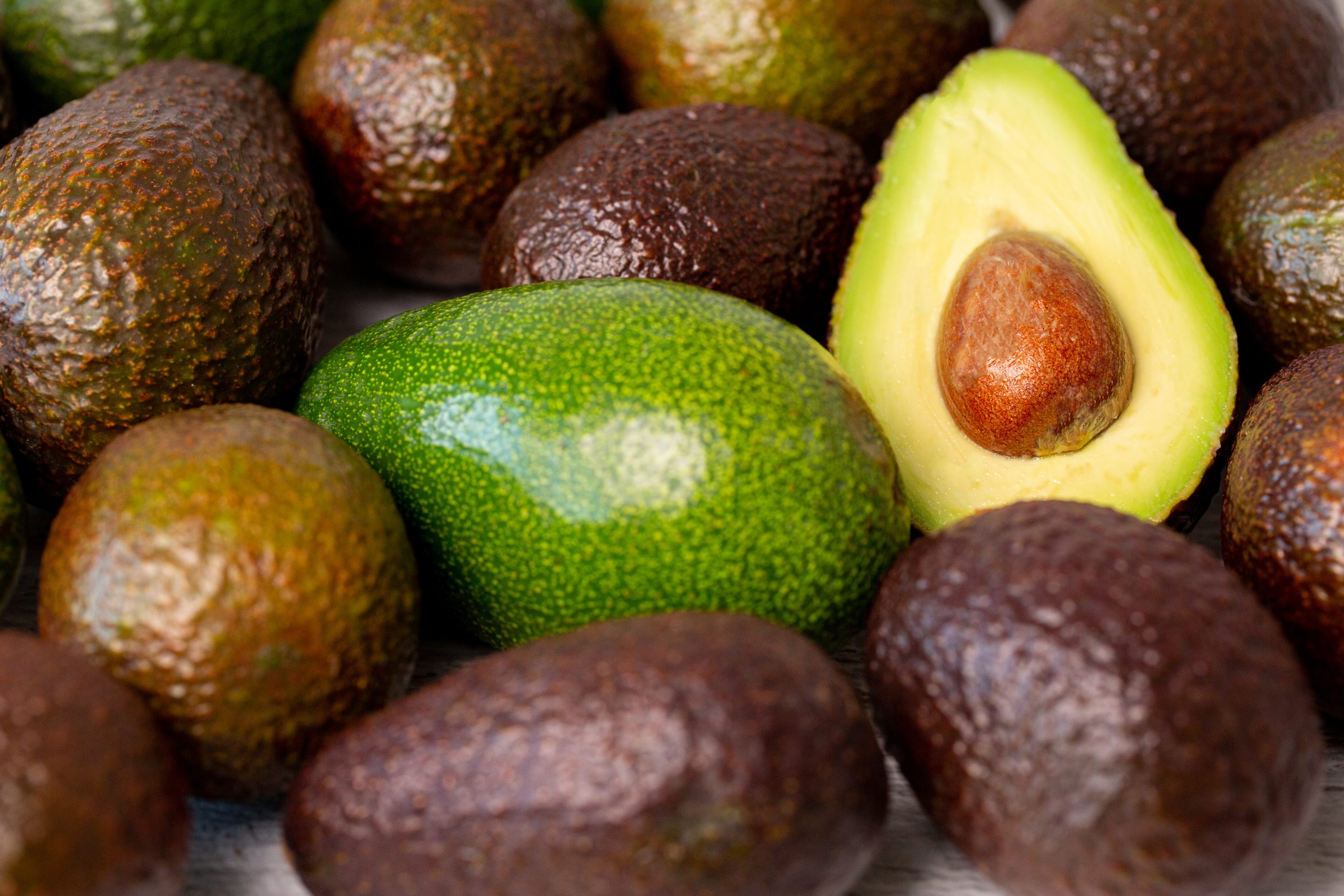 Un avocado a meta vicino ad avocadi interi (fonte: FreePik)