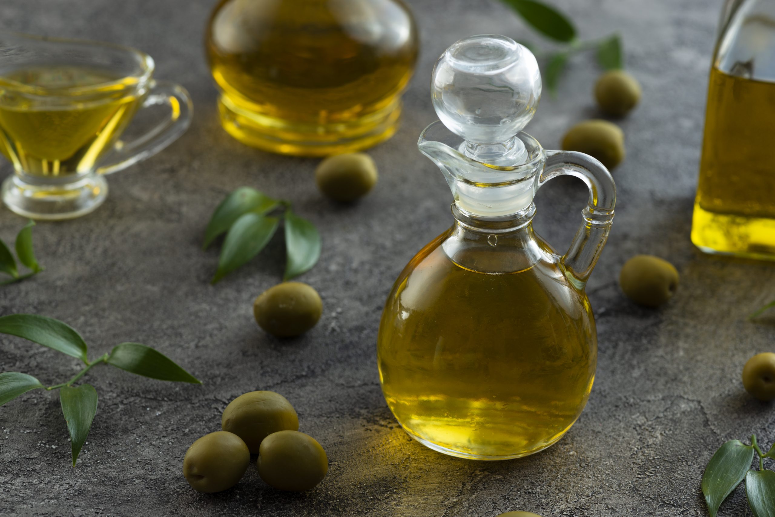 Una bottiglia di olio d'oliva vicino a delle olive (fonte: FreePik)